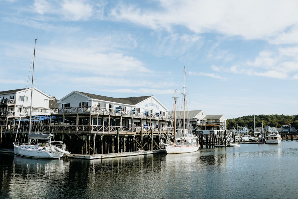 Beautiful harbor scene in Maine with sailboats and waterfront buildings under a clear sky.
